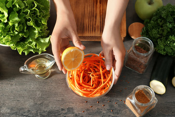 Woman preparing carrot salad in kitchen