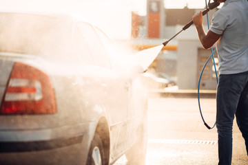 Fototapeta na wymiar Male worker wash the car with high pressure washer