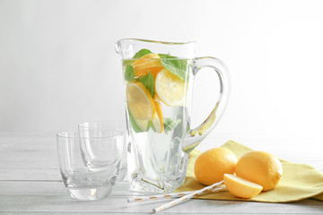 Jug and glasses with refreshing lemon water on wooden table