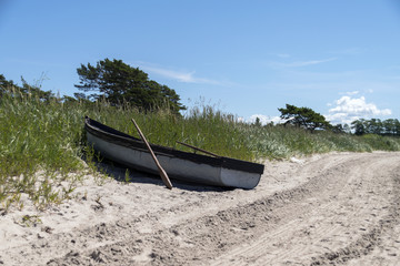 En liten båt av trä liggande på en sandstrand
