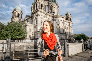 Fototapeta na wymiar Young woman tourist with photo camera enjoying traveling in Berlin city walking near the famous cathedral