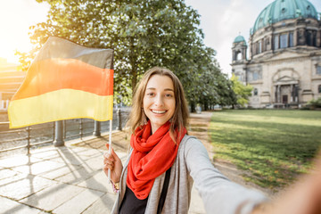 Young woman tourist making selfie photo with german flag in front of the famous cathedral in Berlin city © rh2010
