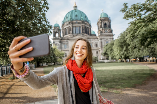 Young woman tourist making selfie photo in front of the famous cathedral in Berlin city