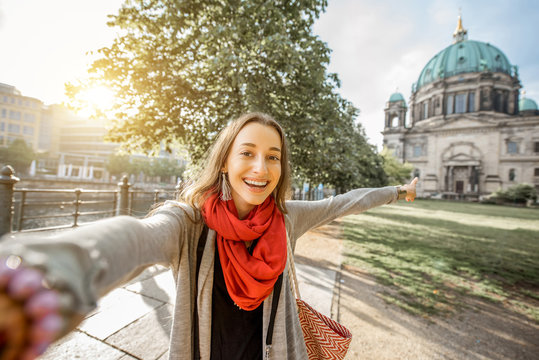 Young woman tourist making selfie photo in front of the famous cathedral in Berlin city