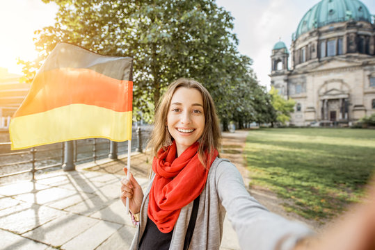 Young woman tourist making selfie photo with german flag in front of the famous cathedral in Berlin city