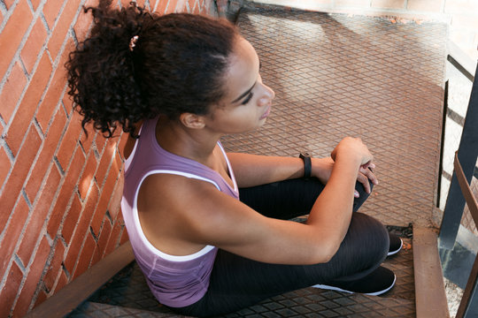 Top view of a sports woman resting after training, sitting on staircase