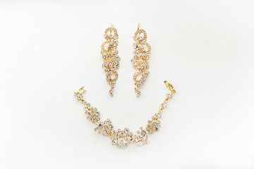 Gold woman jewelry on white background. Earrings and bracelet pu