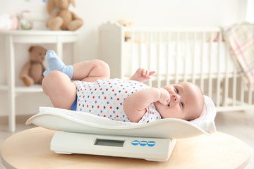 Baby lying on scales in room