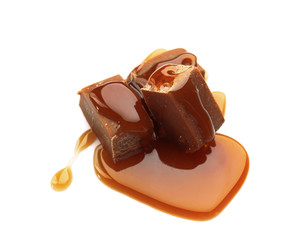 Tasty caramel sauce with candies on white background