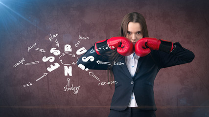 Fototapeta na wymiar Woman in red boxing gloves standing near wall with a business idea sketch drawn on it. Concept of a successful business.