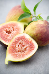 Whole figs and one fig sliced in half on top of a gray table.