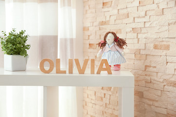 Baby name OLIVIA composed of wooden letters on shelf. Choosing name concept