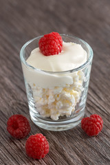 With cream cheese and raspberries in a small Cup on a wooden table.