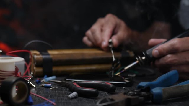 EVIL MAN MAKING A BOMB.  SLOW, CLOSE UP DOLLY PUSH IN.