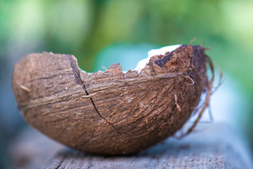 half coconut rests on a wooden cutting board against green background. selective focus macro shot with shallow DOF