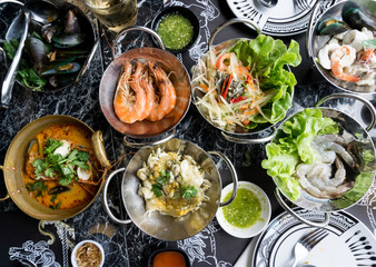 Thai seafood on table Include Tom Yum Goong, Papaya salad, Oyster Omelette, Raw shrimp. .