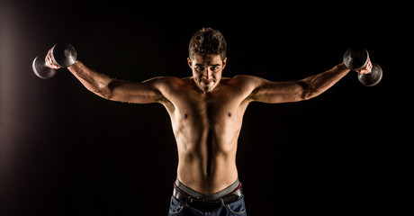 Man stretching arms outward doing a Standing Dumbbell Chest Fly. Studio composite over black.