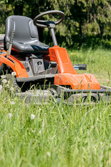 Obraz premium lawn mower cutting green grass in backyard. work in the garden.