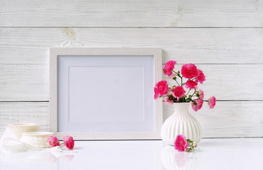 Fototapeta na wymiar White frame mockup with pink roses in white vase. Copy space