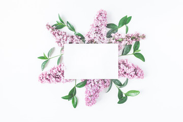 Flowers mock up. Pink lilac flowers, green leaves and paper blank on white background. Flat lay,...