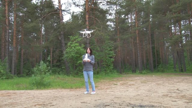Girl Controls Drone. 
Girl runs by remote control drone in the woods
