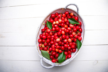 Red cherries in white basket on white wooden background. Cherry close up. Top view.
