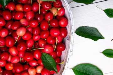 Red cherries in white basket on white wooden background. Cherry close up. Top view.