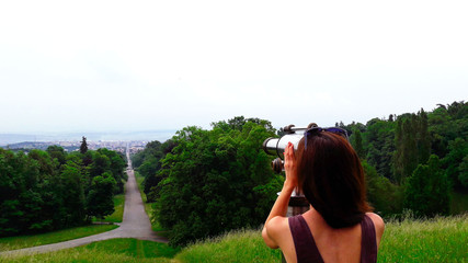 Obraz premium Picture of woman looking through binoculars at the city landscape