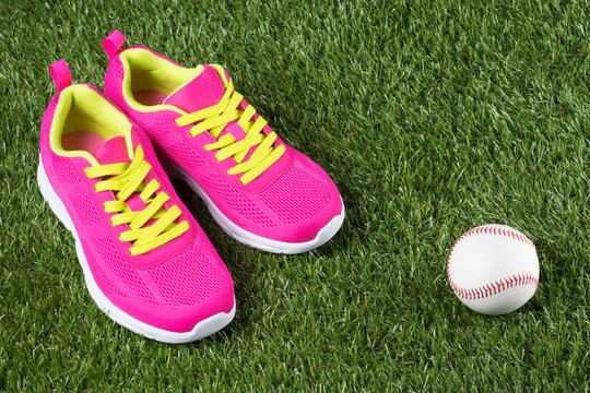 Pink sneakers and ball lie on green grass