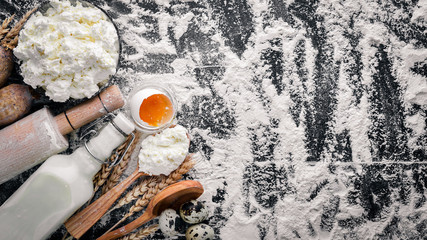 Preparation for baking, cheese sour cream, milk, flour, eggs. On a black wooden background. Top view. Free space.