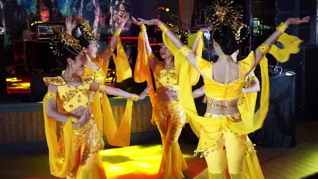 group of five asian women actresses in traditional thai yellow costumes dancing