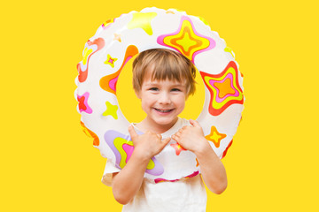 little boy with a rubber ring for swimming on a yellow background. summer beach concept..