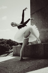 Young woman in white tutu dancing in the green  landscape. Beautiful ballerina showing classic...