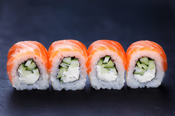 Philadelphia sushi rolls served on black slate, close up. Delicious Japanese seafood