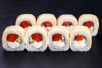 Delicious sushi rolls in grilled cheese served on black slate, close up. Japanese traditional and healthy food