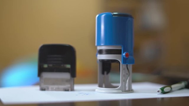 Young woman working in office with papers. Deaet approval by stapping with a seal on paper. Diverse ways to press