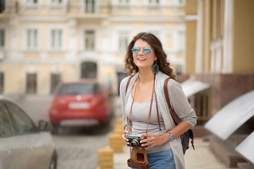 Fototapeta na wymiar Happy young woman traveling in Europe.Girl with long brown hair smiling and holding camera in her arms.