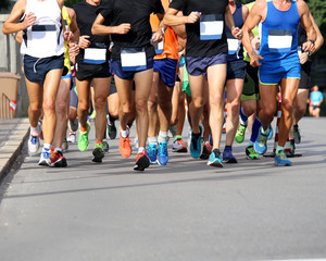 Fototapeta na wymiar Muscular legs of athletes running the marathon on the city stree