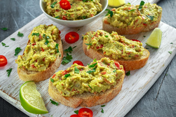 Homemade Guacamole toast with chili pepper, parsley on white wooden board