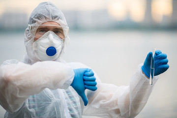 Biologist in respirator with test-tube