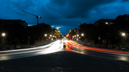 Fork of the road in Munich during the night time long exposure cars are casting light traces 