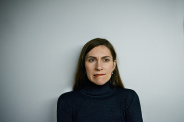 Fototapeta premium Human facial expressions, emotions, feelings and attitude. Indecisive concentrated beautiful girl biting her lip, having doubftul look, absorbed in thoughts, looking for solution to some problem
