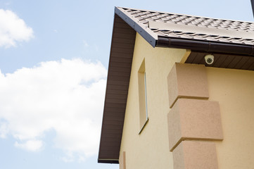 Modern private house with a surveillance camera on it, beautiful sky background