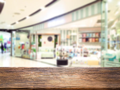 Abstract blur and defocused beautiful luxury shopping mall department and retail store interior for background and empty wooden table space platform for present product.