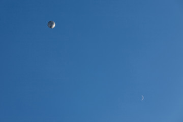 Black and white balloon in flight and moon seen from below