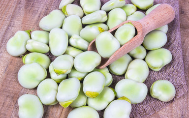 Green fresh broad beans on old wooden table.