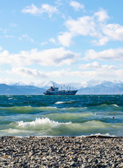 Seascape, ship floating away into the distance, mountains, sky, stones