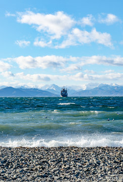 Seascape, ship floating away into the distance, mountains, sky, stones