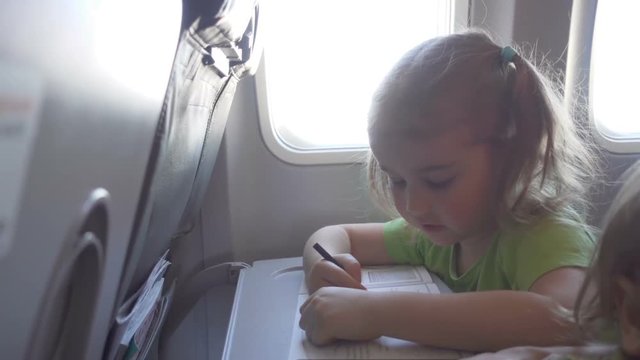 Little girl child draws,  sitting on the board of plane.