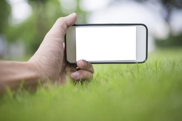 Close up man hand using smartphone in green park, Mockup of blank screen of smartphone